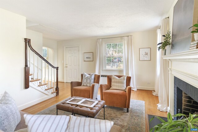 living area featuring stairway, a fireplace, baseboards, and wood finished floors