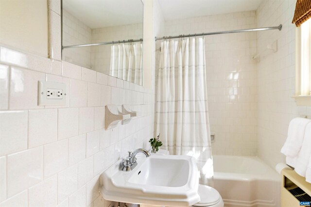 bathroom with shower / bathtub combination with curtain, toilet, a sink, backsplash, and tile walls