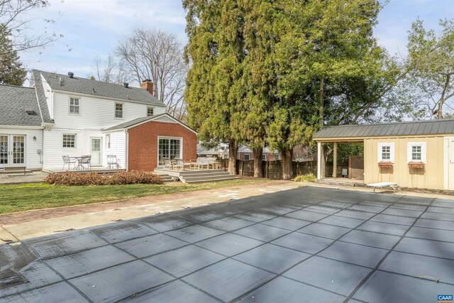 rear view of property featuring brick siding, fence, a chimney, and a patio area