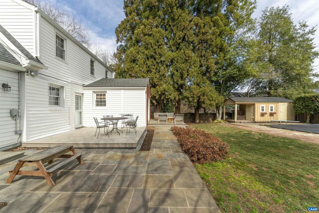 view of patio with outdoor dining space, an outdoor structure, fence, and a wooden deck