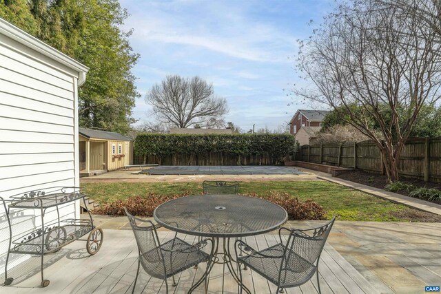 wooden terrace with an outbuilding, outdoor dining area, and a fenced backyard