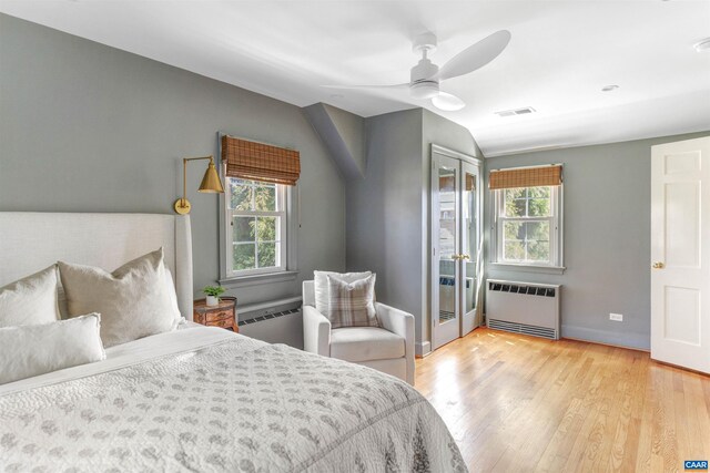 bedroom with multiple windows, radiator heating unit, visible vents, and light wood-type flooring