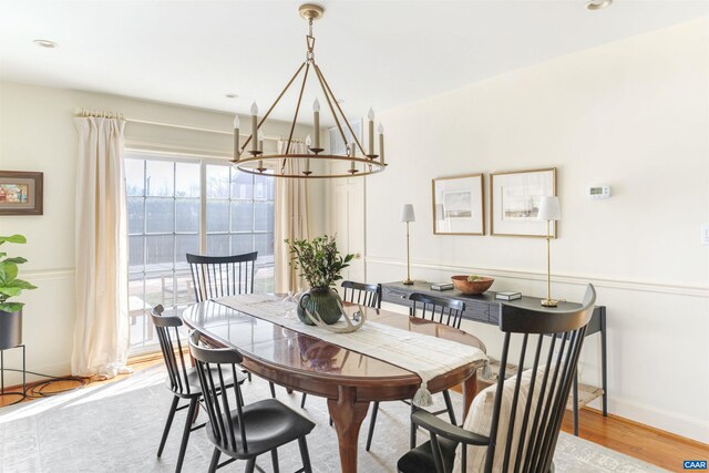 dining space featuring baseboards, a chandelier, and light wood finished floors