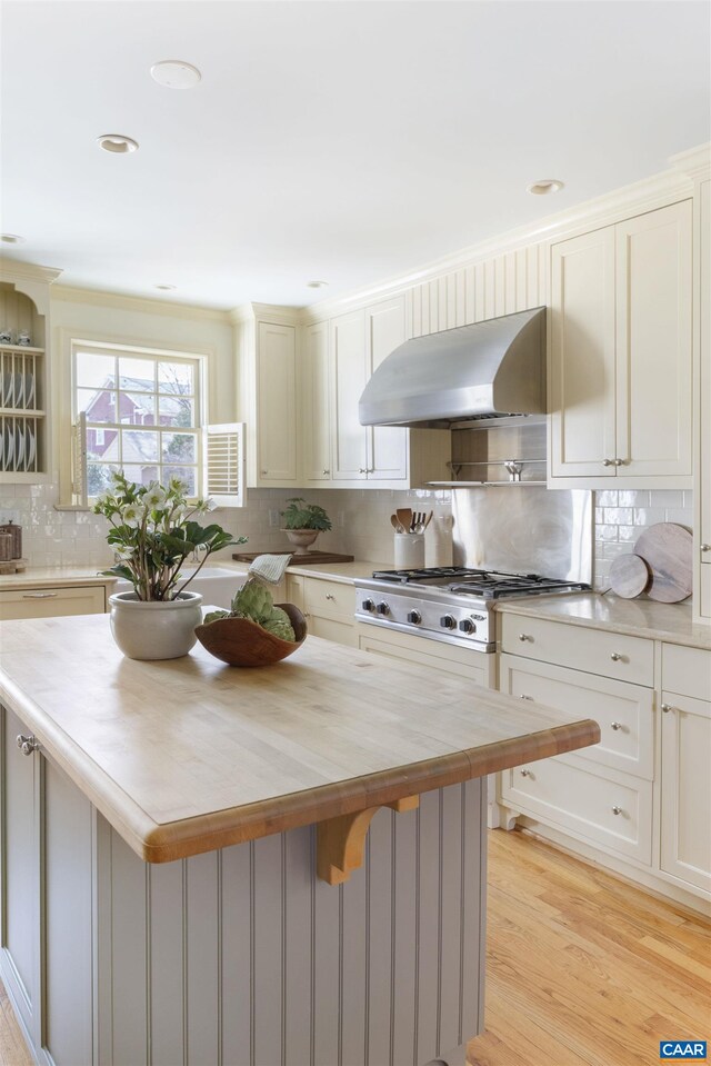 kitchen featuring backsplash, wooden counters, a center island, ventilation hood, and light wood-type flooring