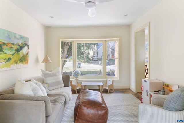 living area featuring baseboards and ceiling fan