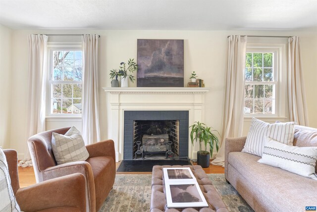 living room featuring a fireplace with flush hearth, a healthy amount of sunlight, and wood finished floors