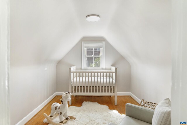 bedroom with baseboards, wood finished floors, and vaulted ceiling