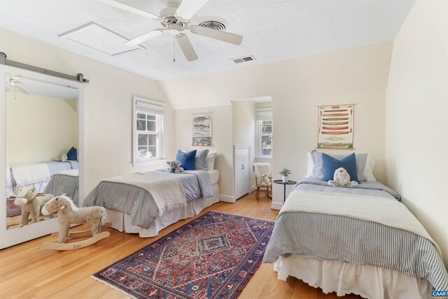 bedroom with visible vents, vaulted ceiling, wood finished floors, a textured ceiling, and a ceiling fan