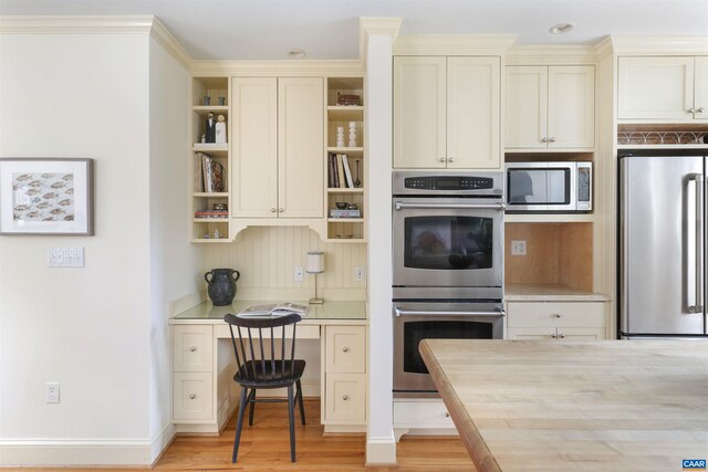 kitchen featuring light wood-type flooring, cream cabinetry, open shelves, stainless steel appliances, and light countertops