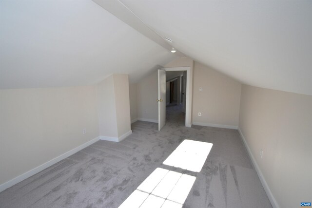 bonus room with light colored carpet and vaulted ceiling