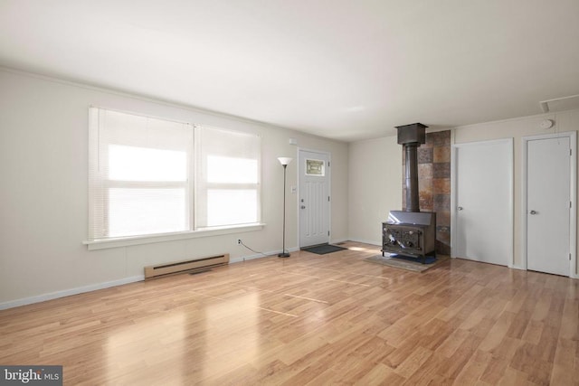 unfurnished living room with a baseboard radiator, light hardwood / wood-style flooring, and a wood stove