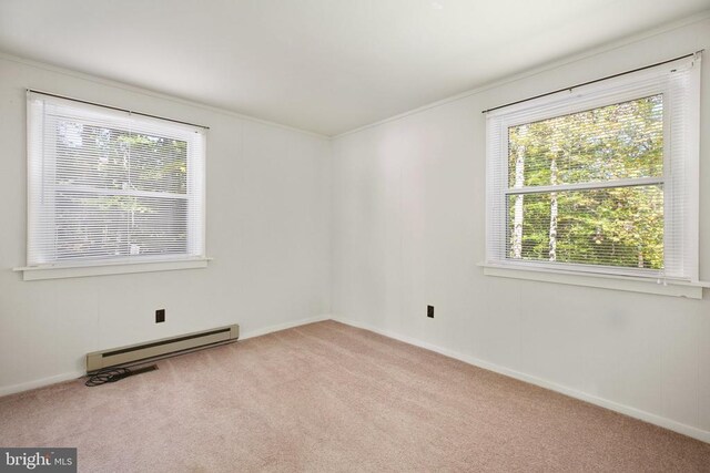 spare room featuring crown molding, a baseboard heating unit, and light carpet