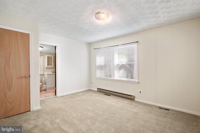 carpeted empty room featuring sink, a textured ceiling, and baseboard heating