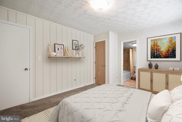 bedroom with ensuite bath, carpet floors, and a textured ceiling