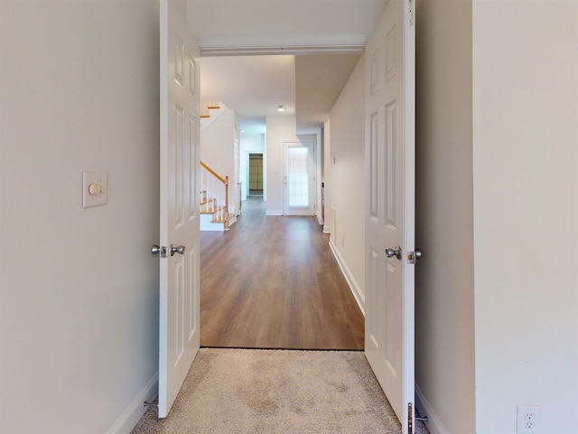 hallway featuring baseboards and stairs