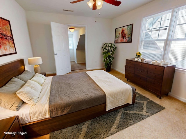 bedroom featuring baseboards, multiple windows, ceiling fan, and light colored carpet