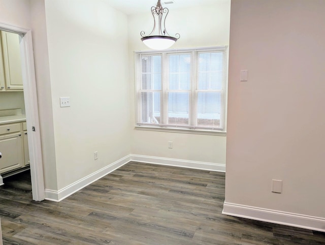 unfurnished dining area featuring baseboards and dark wood-type flooring