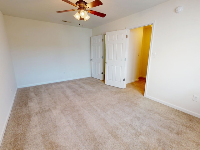 carpeted empty room featuring baseboards, a ceiling fan, and visible vents