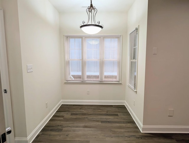 unfurnished dining area with baseboards and dark wood-style floors