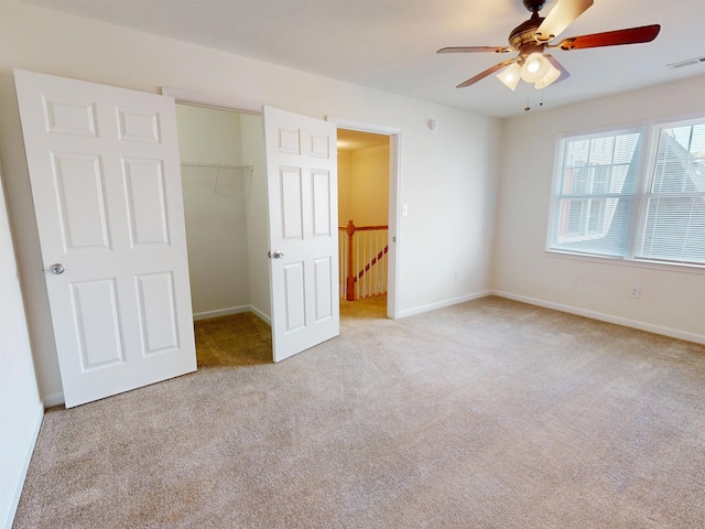 unfurnished bedroom featuring visible vents, a closet, baseboards, a walk in closet, and carpet flooring
