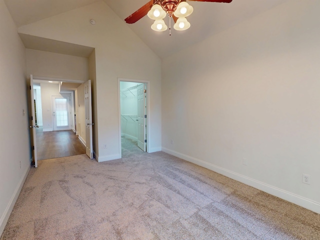 unfurnished bedroom featuring a closet, baseboards, a walk in closet, high vaulted ceiling, and carpet