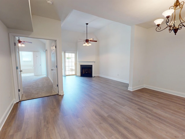 unfurnished living room with baseboards, ceiling fan with notable chandelier, and wood finished floors