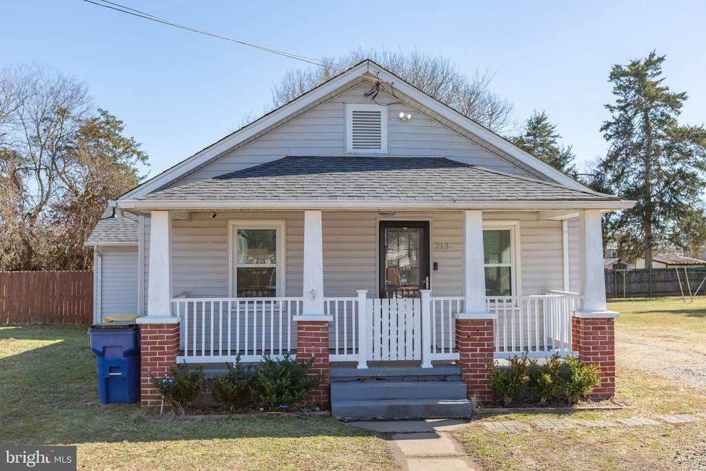 bungalow with covered porch, a shingled roof, a front yard, and fence