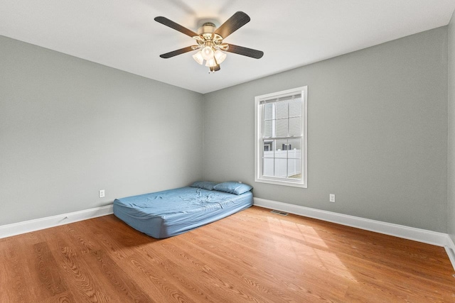 unfurnished bedroom featuring visible vents, ceiling fan, baseboards, and wood finished floors