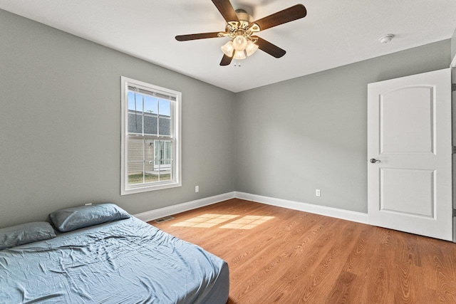 bedroom with ceiling fan, baseboards, visible vents, and light wood-style flooring