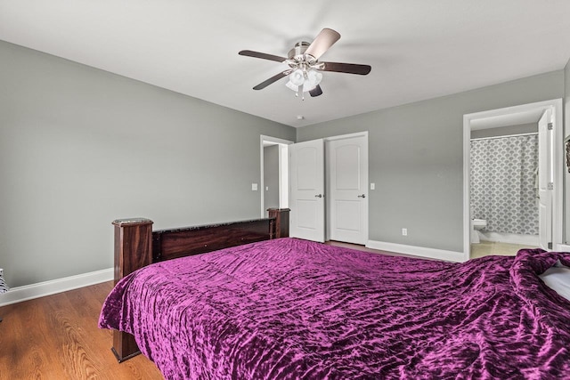 bedroom featuring a ceiling fan, ensuite bath, baseboards, and wood finished floors