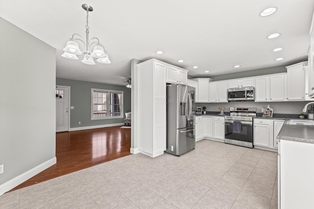 kitchen with stainless steel appliances, dark countertops, recessed lighting, white cabinets, and a sink