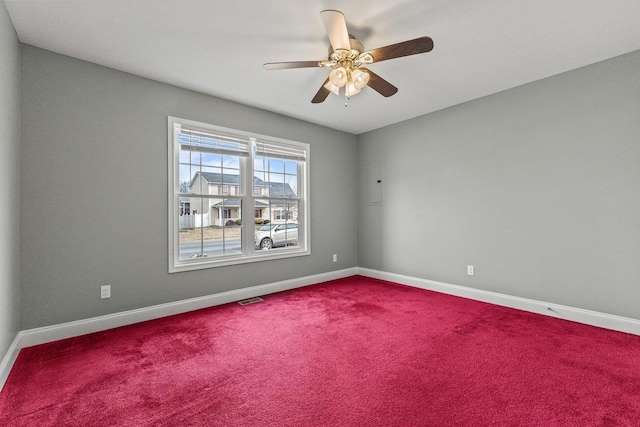 empty room featuring ceiling fan, dark colored carpet, visible vents, and baseboards