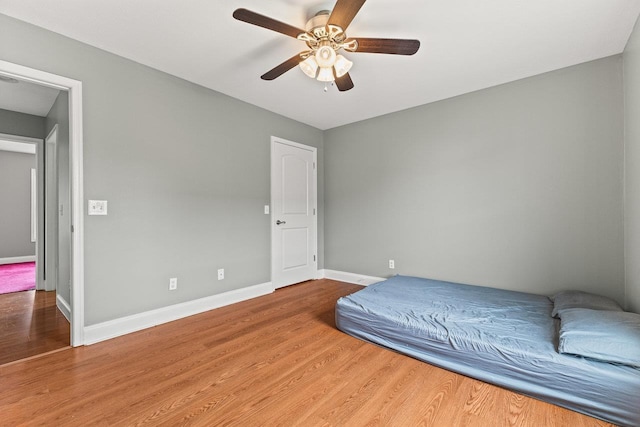 bedroom featuring ceiling fan, baseboards, and wood finished floors