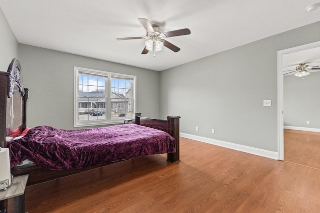 bedroom with ceiling fan, baseboards, and wood finished floors