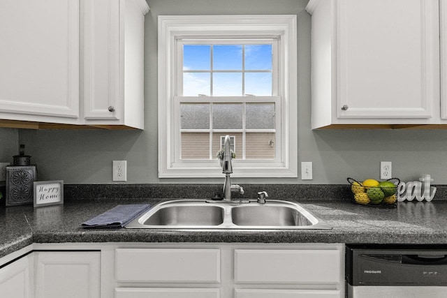 kitchen with a sink, dark countertops, white cabinets, and dishwasher