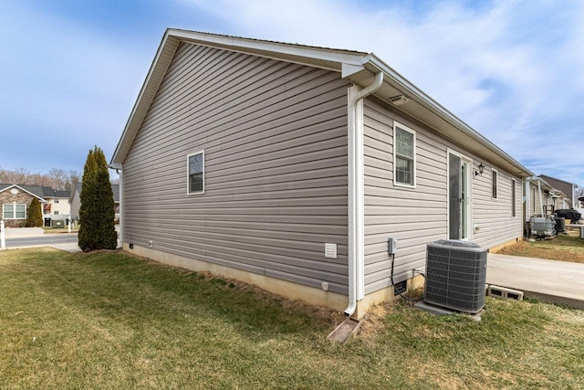 view of side of property with central AC unit and a lawn