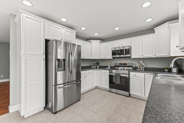 kitchen featuring light tile patterned floors, white cabinetry, appliances with stainless steel finishes, and a sink