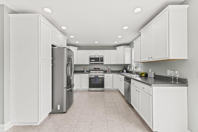 kitchen with dark countertops, stainless steel appliances, a sink, and recessed lighting