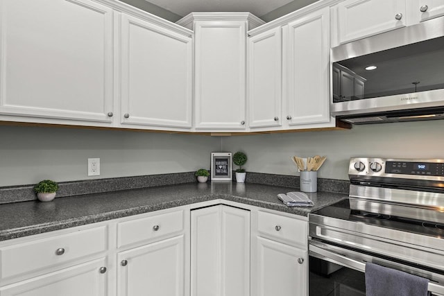 kitchen with appliances with stainless steel finishes, dark countertops, and white cabinetry