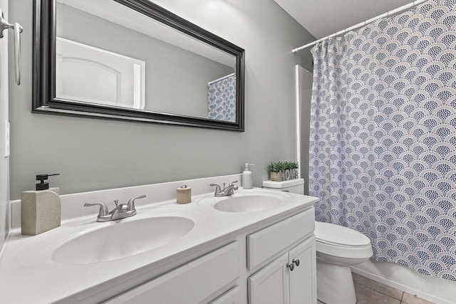 bathroom featuring toilet, double vanity, a sink, and tile patterned floors