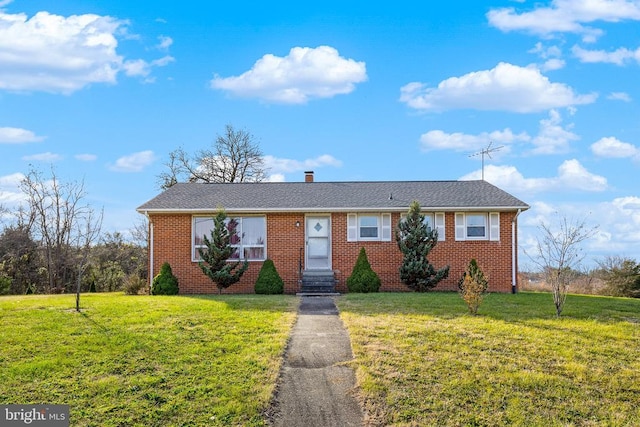 single story home featuring brick siding, a chimney, and a front yard