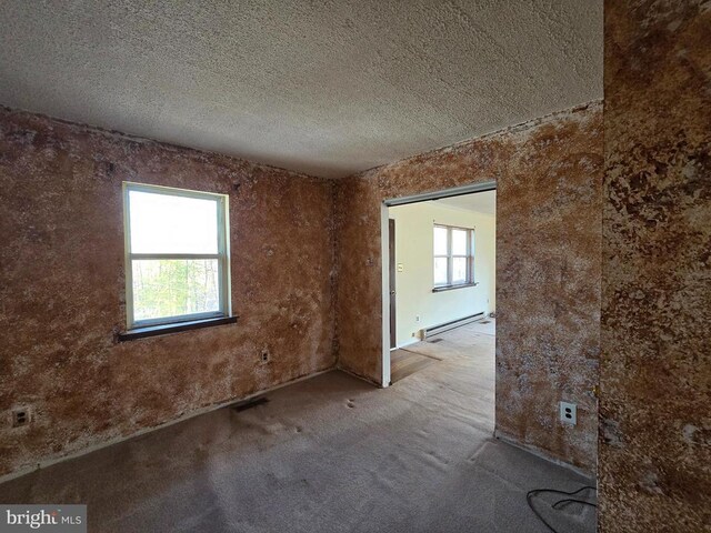 unfurnished room with a baseboard heating unit, light carpet, and a textured ceiling