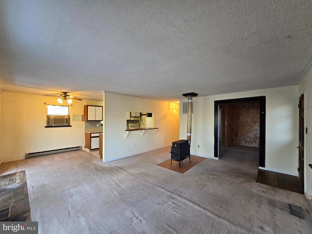 unfurnished living room with a baseboard heating unit, carpet, ceiling fan, and a wood stove