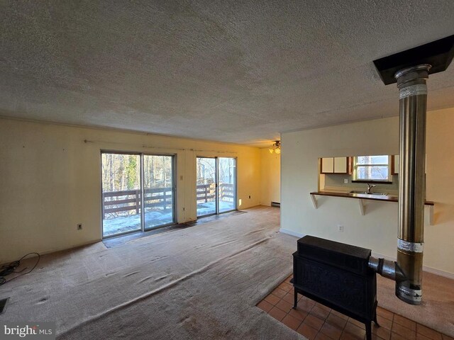 unfurnished living room with sink, ceiling fan, a textured ceiling, and carpet flooring