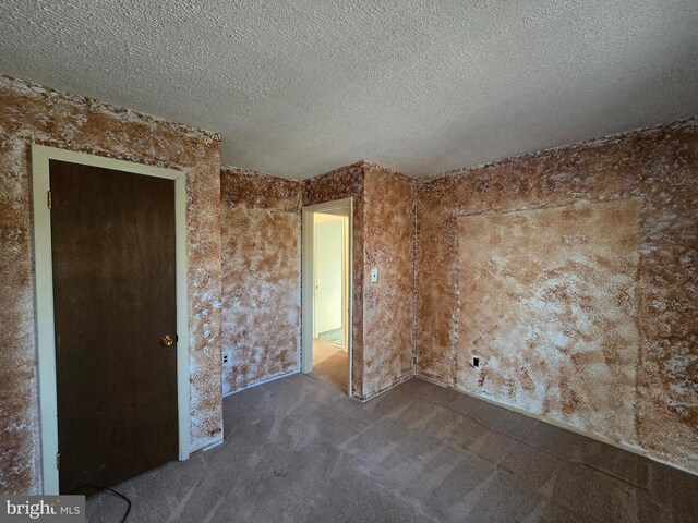 unfurnished bedroom with dark colored carpet and a textured ceiling