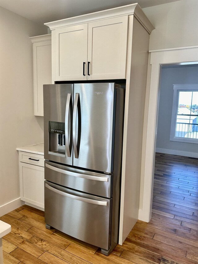 kitchen featuring light hardwood / wood-style flooring, white cabinets, and stainless steel refrigerator with ice dispenser