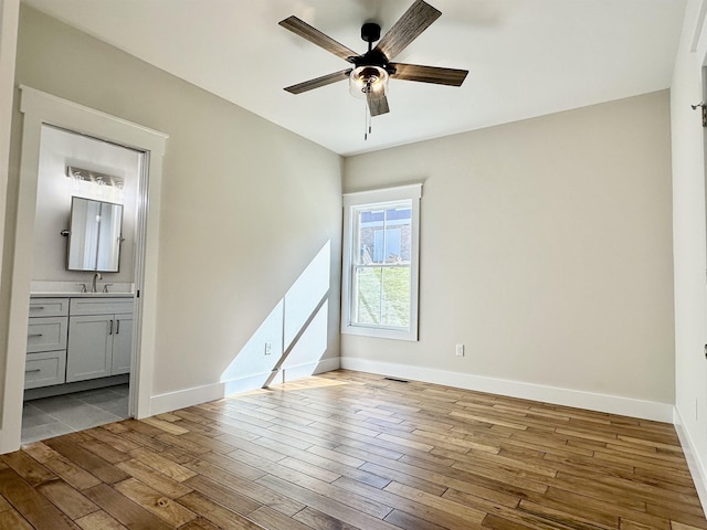 spare room featuring ceiling fan, sink, and light wood-type flooring