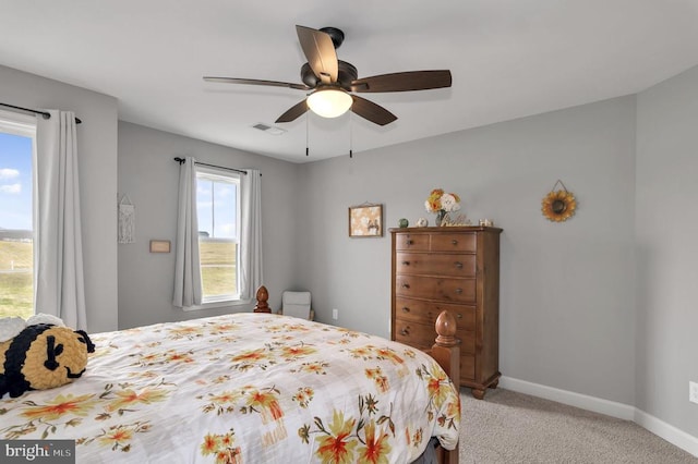 bedroom with a ceiling fan, light colored carpet, visible vents, and baseboards