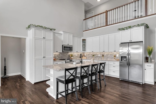 kitchen with light stone countertops, appliances with stainless steel finishes, dark wood-style floors, and white cabinetry