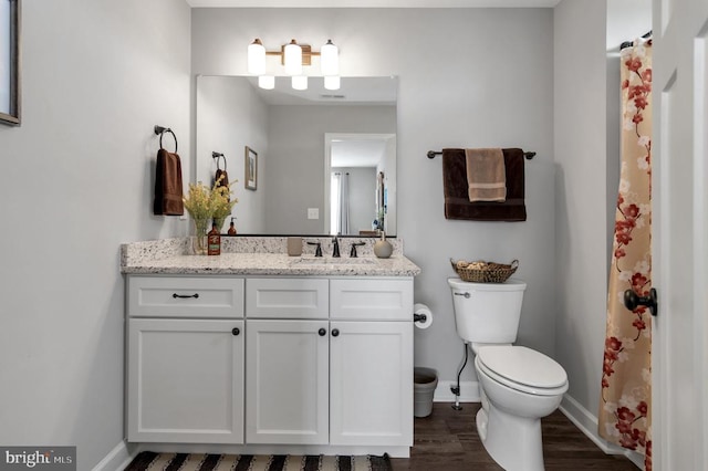 bathroom with vanity, toilet, wood finished floors, and baseboards